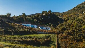 A hillside with modern white buildings, surrounded by lush greenery and hills. - Luxury fiore suites 3 (Zakinthos)
