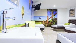 Habitación de hotel con un ventanal grande, un lavamanos, dos camas y un mural de un paisaje con globos aerostáticos.