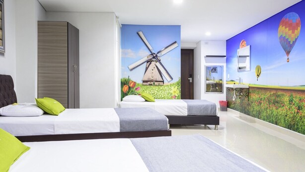 Habitación de hotel con dos camas, un gran mural de molino de viento y un mural de globo aerostático.