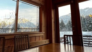 A wooden interior with large windows, a table, and a chair. - Spacious Luxury View Home: Steps to Hike & Bike, 10pp (Snoqualmie Pass)
