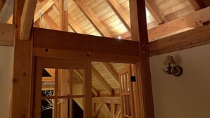 A wooden-framed attic room with a sloped ceiling, a door leading to another room, and a wall-mounted light fixture. - Spacious Luxury View Home: Steps to Hike & Bike, 10pp (Snoqualmie Pass)
