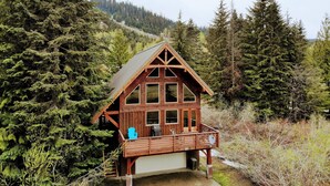 A cabin with a wooden exterior, large windows, and a balcony. - Spacious Luxury View Home: Steps to Hike & Bike, 10pp (Snoqualmie Pass)