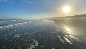 Ein Strand mit wolkenlosem Himmel und tief stehender Sonne.