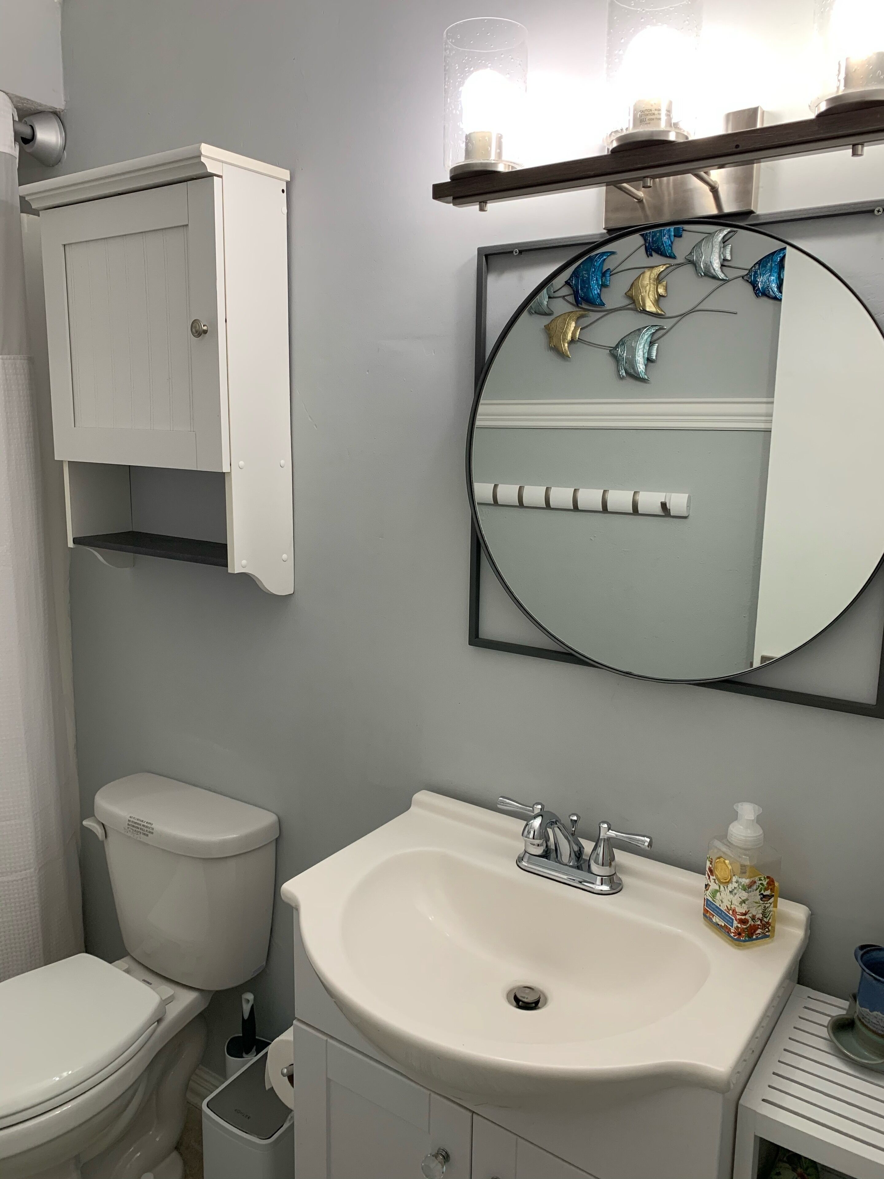 A bathroom with a toilet, sink, and cabinet.