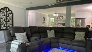 Ein modernes Wohnzimmer mit einer Eckcouch, einem gemusterten Teppich und blauer LED-Beleuchtung.