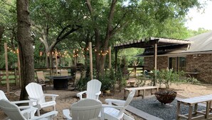 Eine Terrasse mit Adirondack-Stühlen, einer Feuerstelle und einer Pergola.