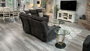 Ein modernes Wohnzimmer mit einer Eckcouch, einem Glastisch und einem Flachbildfernseher.