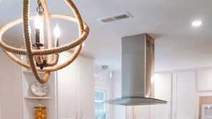 Una cucina con mobili bianchi, un tavolo da pranzo in legno e un lampadario.