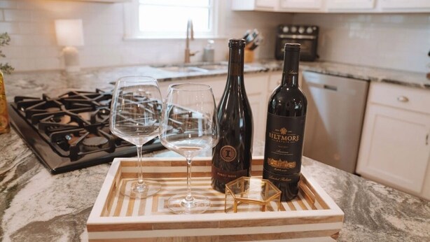 Un ripiano in cucina con una bottiglia di vino, due bicchieri e un vassoio.