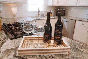 A kitchen counter with a wine bottle, two glasses, and a tray. - ⭕️ Charming Cottage in the heart of Park Circle ⭕️ (North Charleston)