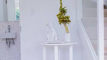 Un baño moderno con un lavabo blanco, un espejo y una pequeña mesa blanca con una planta en maceta.