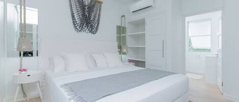 A modern bedroom with a large bed, a wardrobe, a bedside table, and a hanging light fixture.