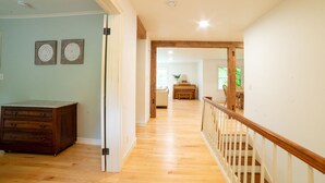 Un hall d’entrée spacieux avec un plancher en bois, un escalier doté d’une rampe en bois, et une vue sur un coin repas avec une table et des chaises.