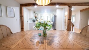 Un coin repas avec une table en bois, un vase de fleurs et un luminaire suspendu moderne.