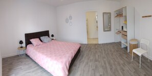 Un dormitorio con cama, mesitas de noche, armario y una silla.