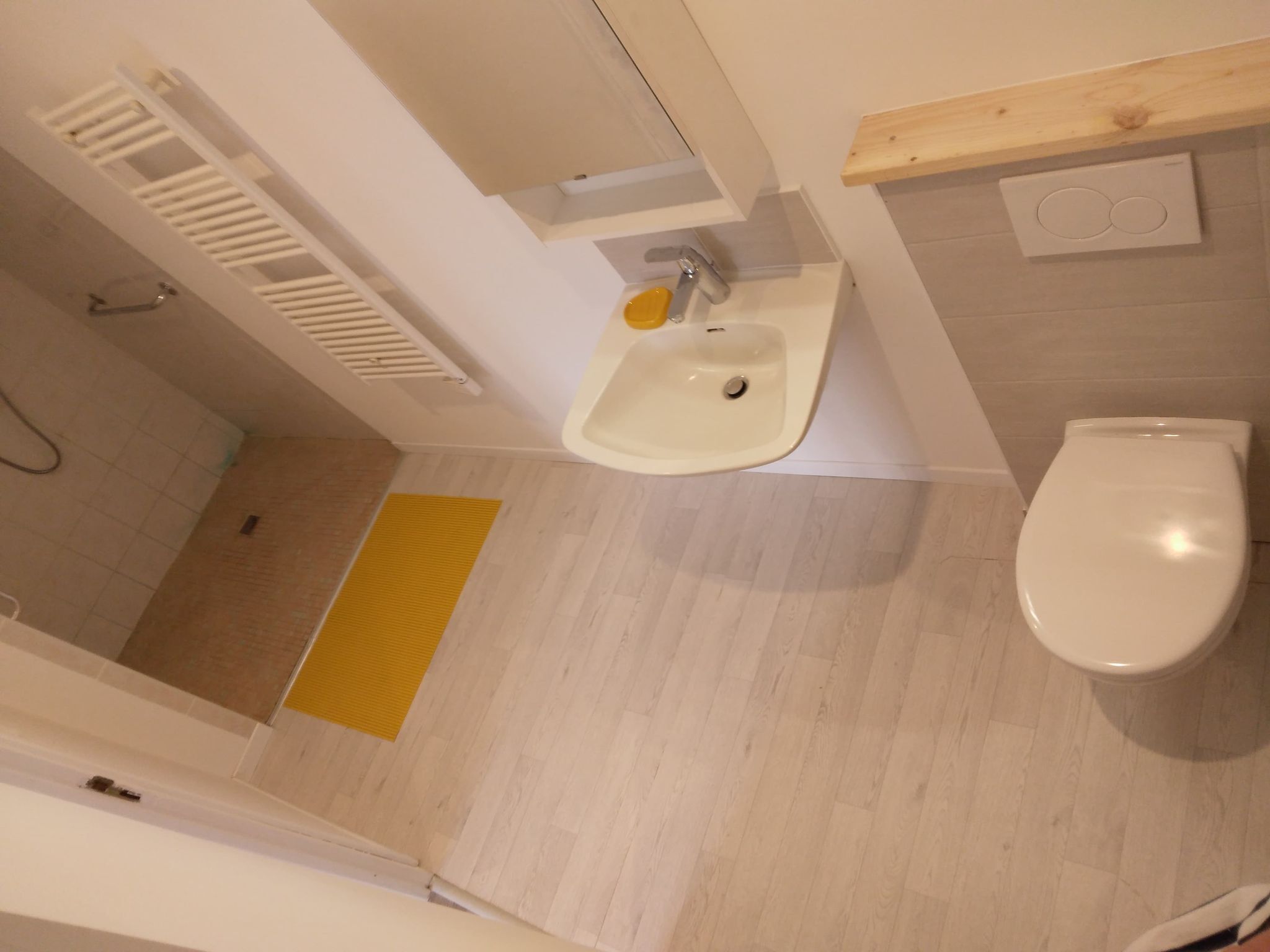 A bathroom with a white sink, a toilet, and a yellow mat on the floor.
