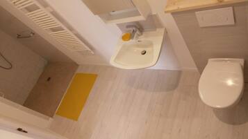 A bathroom with a white sink, a toilet, and a yellow mat on the floor.