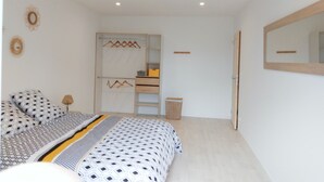 A bedroom with a bed, a wardrobe, a mirror, and a small table. - Grande Longère (ploezal)