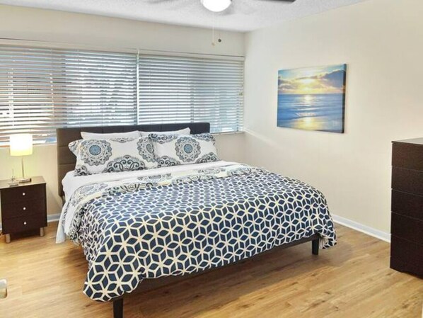 Una camera da letto con un letto, un comodino, una cassettiera e un quadro appeso al muro.