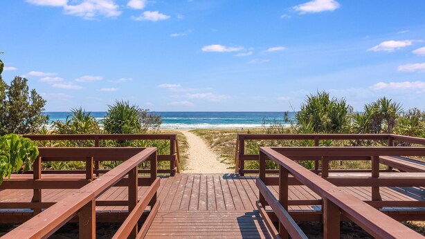 Un paseo marítimo de madera que conduce a una playa con vista despejada al océano.