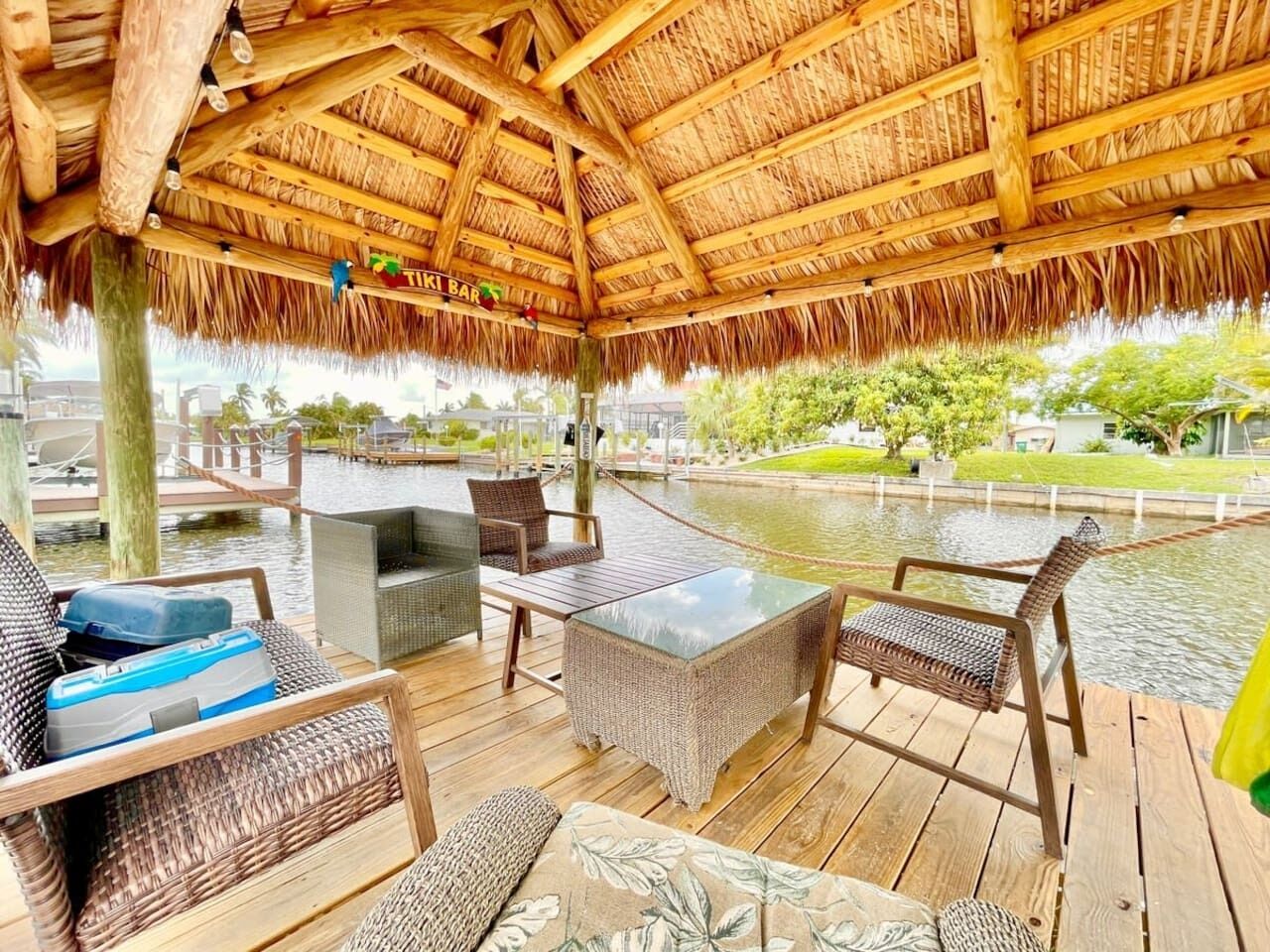 An outdoor seating area with wicker furniture, a thatched roof, and a view of a water body.