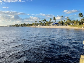 Een strand met kalm water, palmbomen en een heldere lucht.