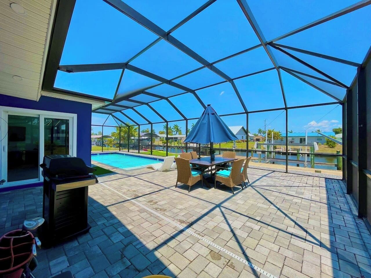 Eine Terrasse im Freien mit Grill, Sitzgelegenheit und Blick auf einen Swimmingpool.