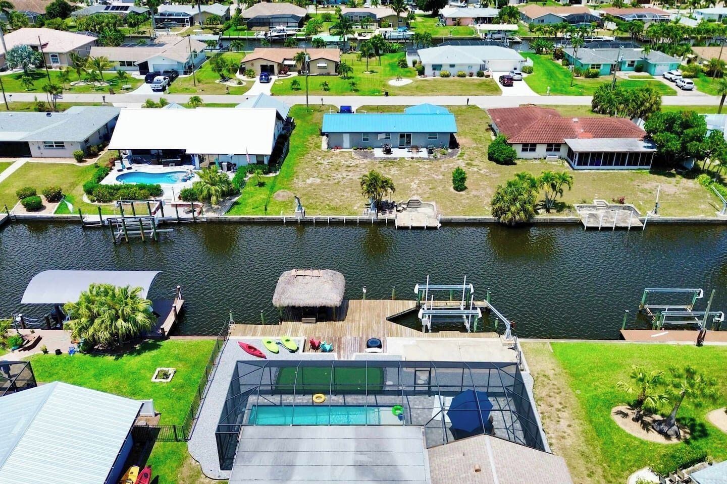 A residential area with a dock, a swimming pool, and houses with various roof colors.