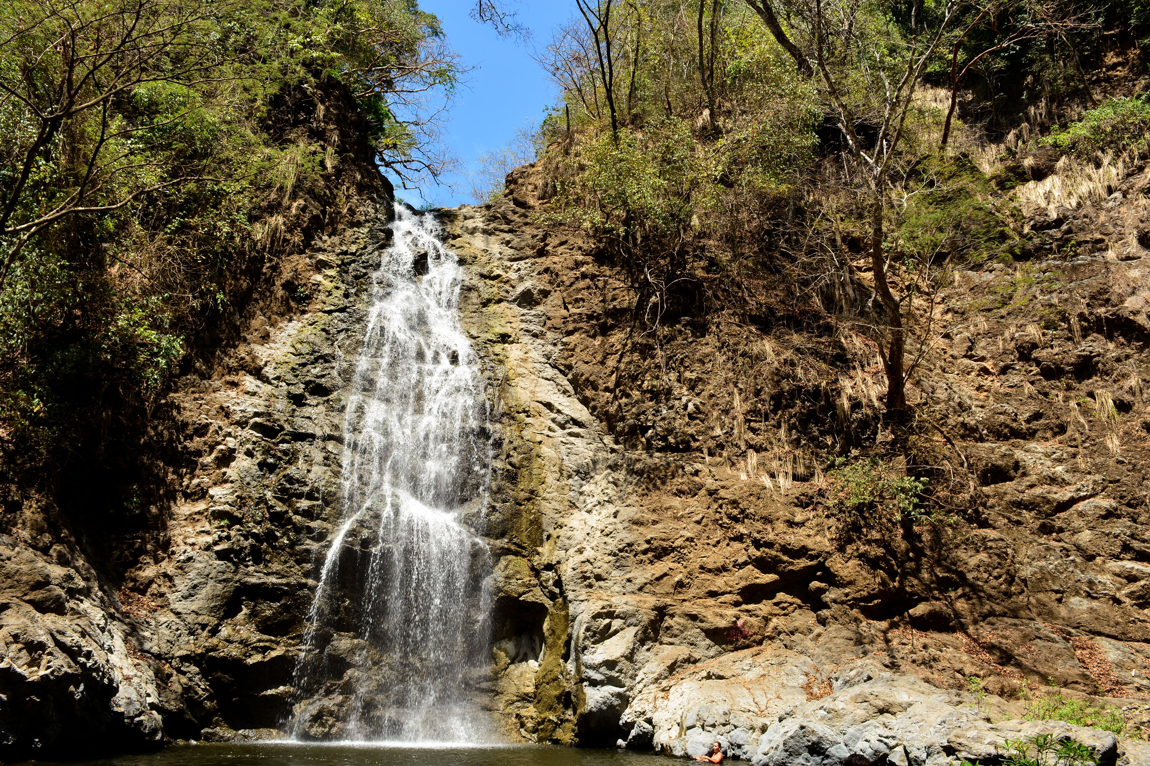 A waterfall cascading down a rocky cliff surrounded by dense forest.