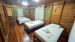 Una habitación tipo cabaña de madera con cuatro camas, cada una con ropa blanca y toallas.