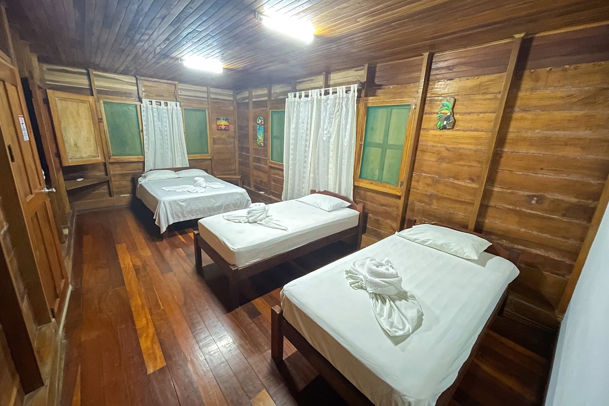 A wooden cabin-style room with four beds, each with white linens and towels.