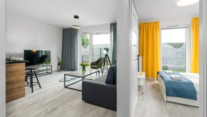 Una sala de estar moderna con un televisor de pantalla plana, un comedor con una mesa de madera y un sofá.