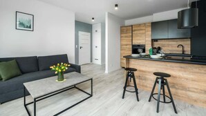 Una cocina moderna con encimera de madera, armarios negros y una lámpara colgante negra.
