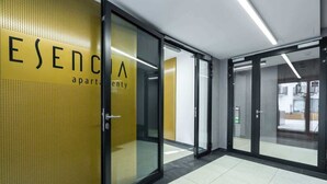 Un interior moderno con puertas de vidrio y una pared amarilla con la palabra 'ESENCA' escrita.