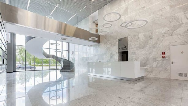 A modern lobby with a marble floor, a white reception desk, and a spiral staircase. - Modern Studio | Parking | Air Conditioning | Close to Expo XXI (Warszawa)