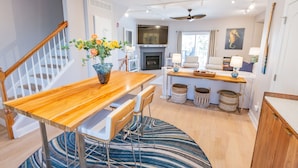 Une cuisine moderne avec une table en bois, des chaises, un vase de fleurs, une cheminée et un ventilateur de plafond.