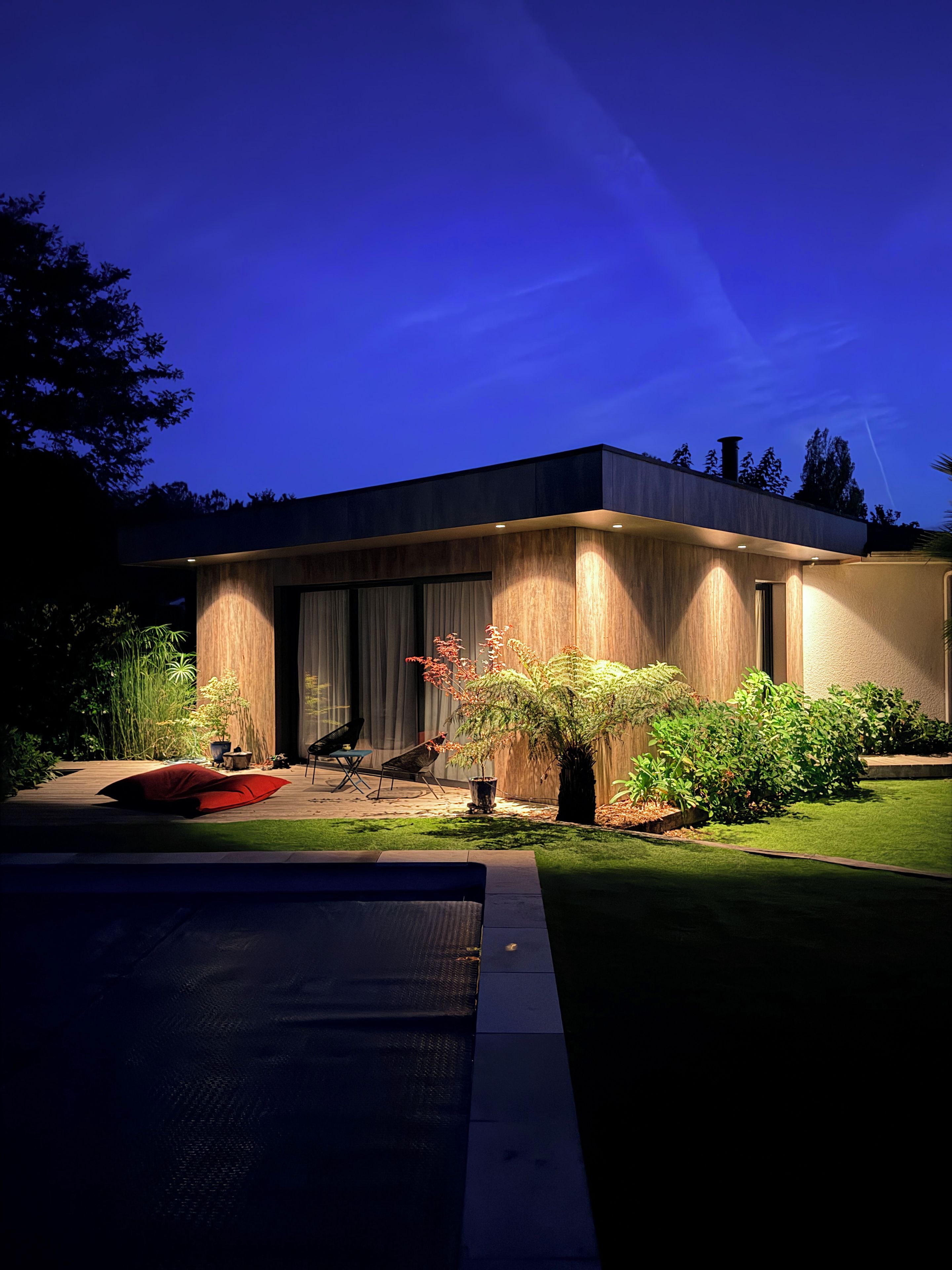 A modern house with a flat roof, large windows, and a well-maintained garden.