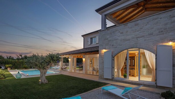 Ein modernes Haus mit Swimmingpool, Sitzgelegenheiten im Freien und einem gut beleuchteten Innenraum.