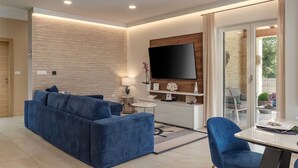 Ein modernes Wohnzimmer mit einem blauen Sofa, einem Flachbildfernseher und einem Essbereich mit einem Glastisch.