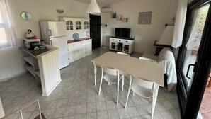 A compact kitchen with a dining area, white cabinetry, a built-in oven, and a TV. - Eden Rock sea View  (Eden Rock)