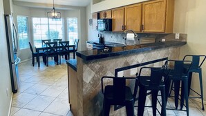 A modern kitchen with a central island, bar stools, and wooden cabinets. - Casa Del Sol Gilbert, Arizona Heated Pool & Hot Tub (Gilbert)