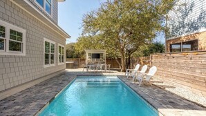 A rectangular swimming pool with a wooden deck and white chairs. - Luxury heated pool & spa home, pool bar, steps to the beach & two master suites! (St. Augustine)