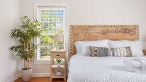 A bedroom with a bed, a bedside table, a lamp, a potted plant, and a window with blinds. - ✰ MARSH VIEW - CHARMING 3BR/2.5BA - BIKES/KAYAKS ✰ (North Charleston)