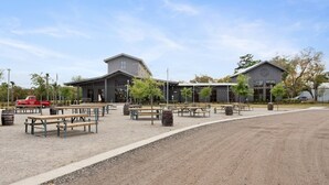 A building with a large patio area, outdoor seating, and a dirt path leading to it. - ✰ MARSH VIEW - CHARMING 3BR/2.5BA - BIKES/KAYAKS ✰ (North Charleston)