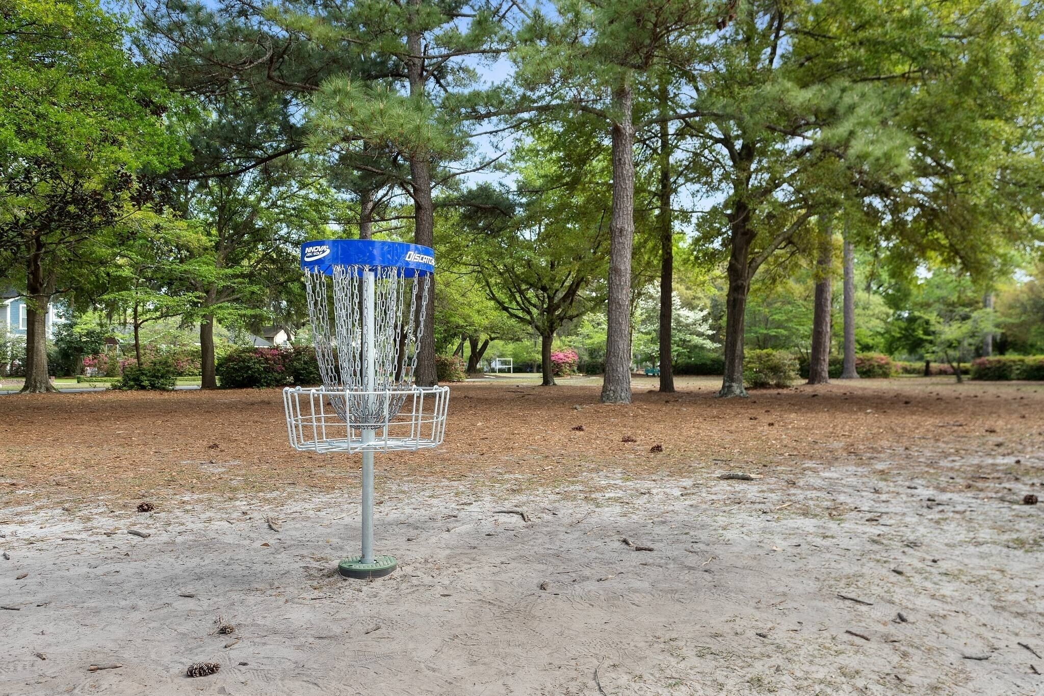 En disc golf kurv i en park med træer og en klar himmel.