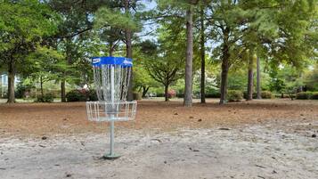 En disc golf kurv i en park med træer og en klar himmel.