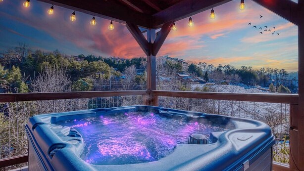 A hot tub with a view of a snowy landscape and a sunset. - Pet friendly,5min2Dollywood,3 kings+loft,Game Room (Pigeon Forge)