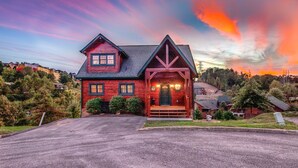 A two-story house with a steeply pitched roof, a front porch, and a driveway leading to the entrance. - Pet friendly,5min2Dollywood,3 kings+loft,Game Room (Pigeon Forge)