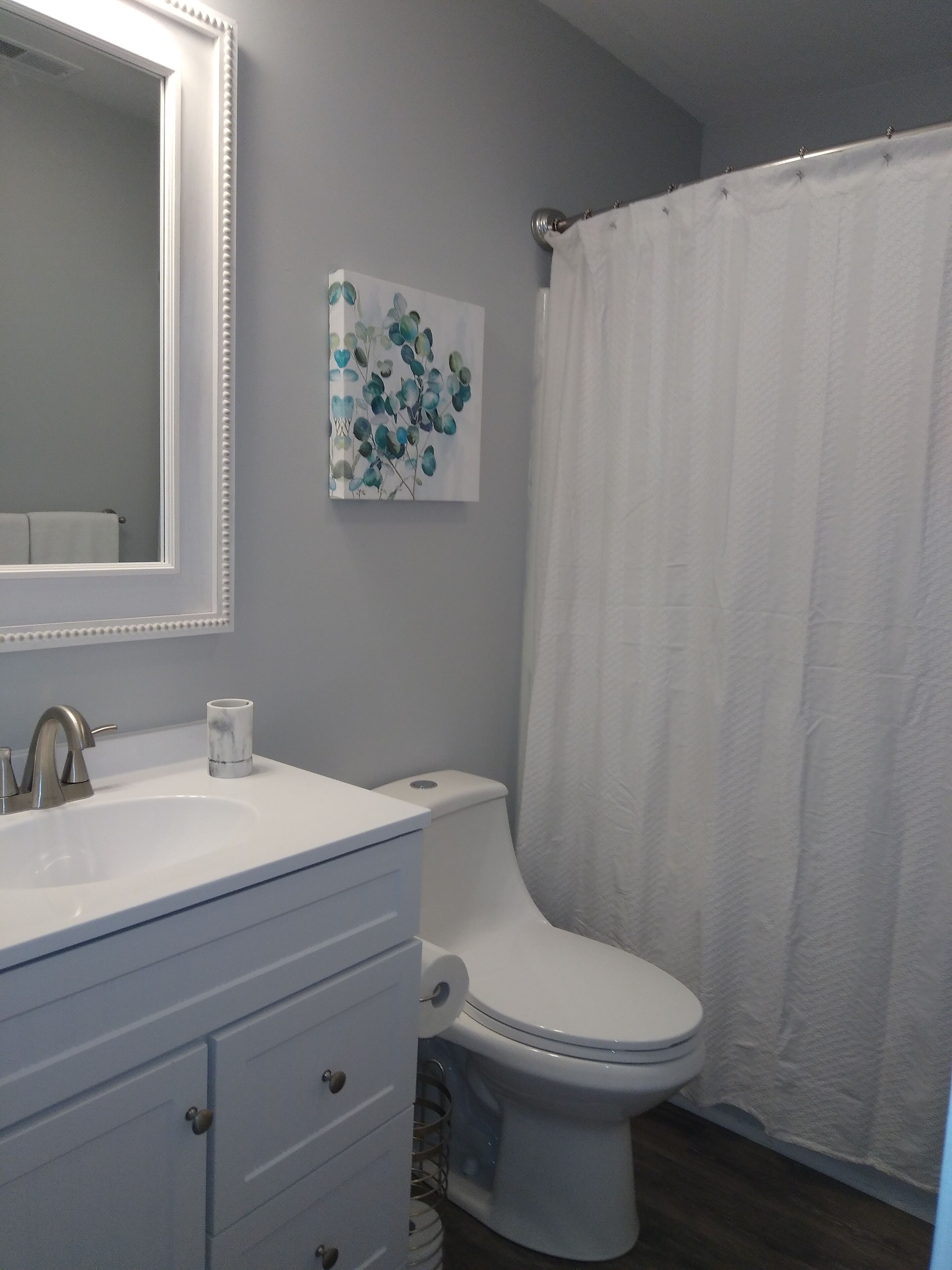 Une salle de bain avec un lavabo blanc, des toilettes et un rideau de douche.