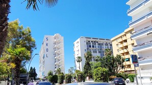 A multi-story building with balconies, a parking sign, and a street with cars and flowers. - Skol 521 - Fantastic Beachfront Studio Holiday Home (Marbella)
